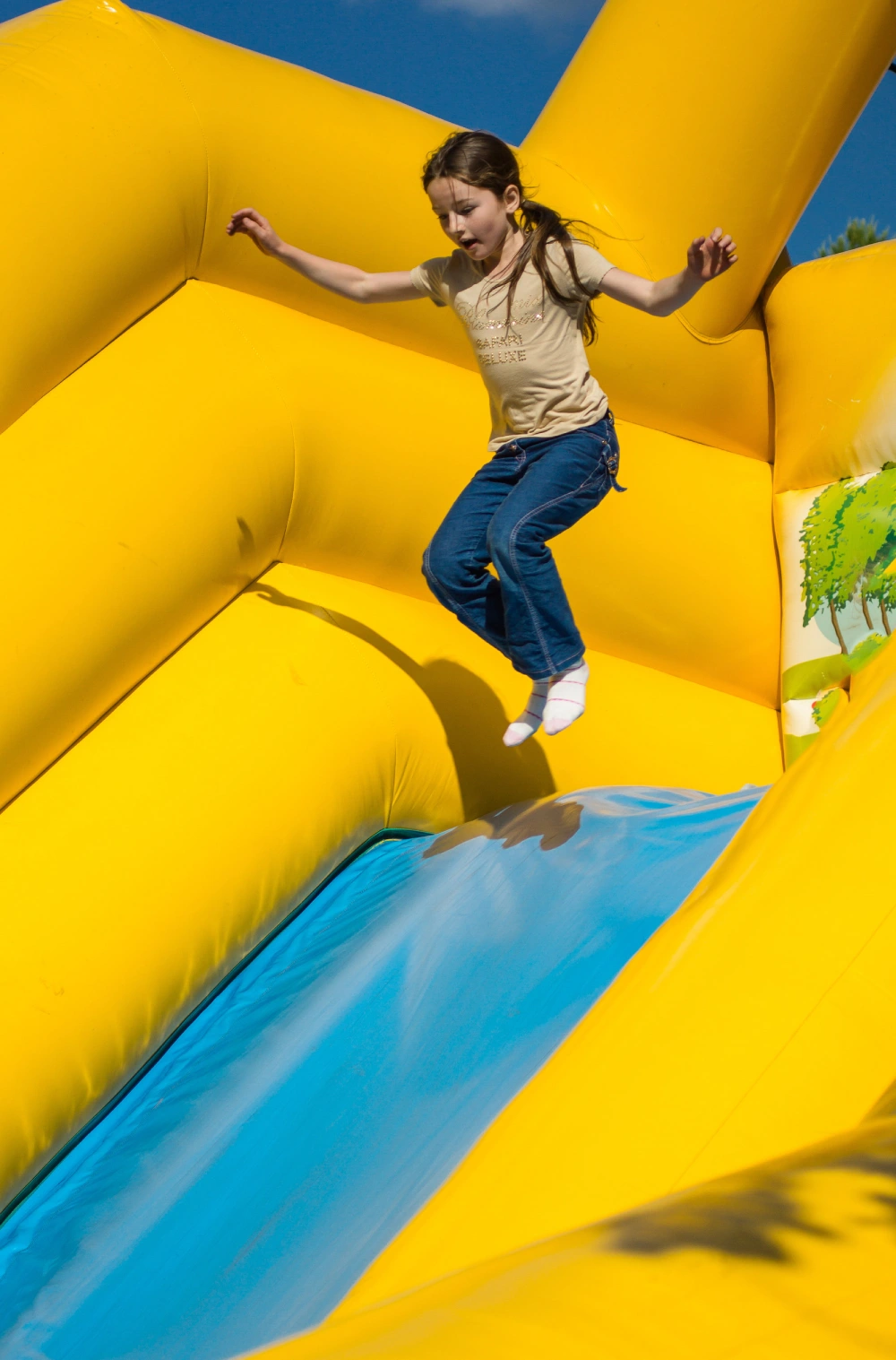 Young girl jumping on attractions. Summer park.